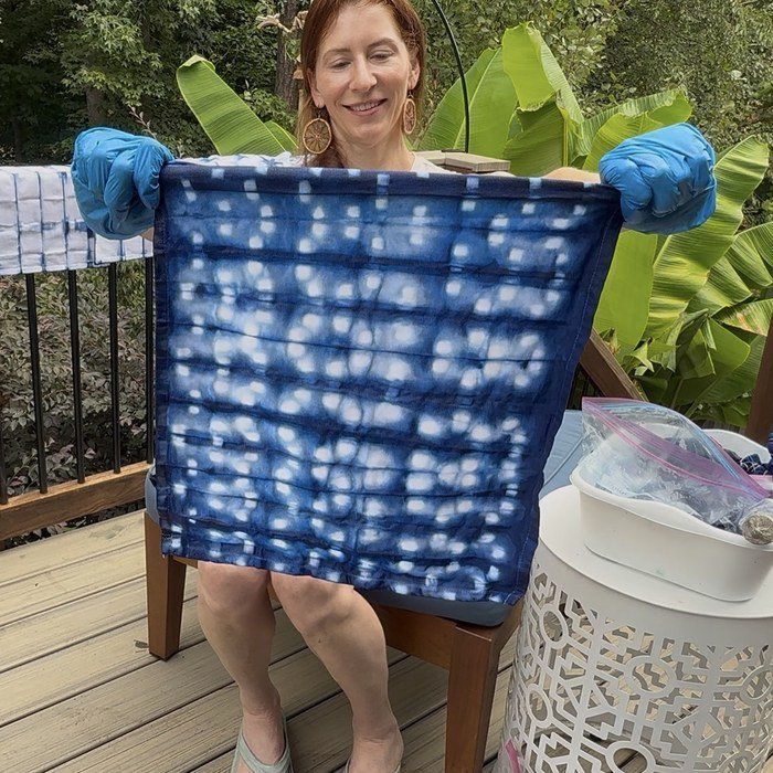 Kristi holding up an unwrapped indigo napkin with rows of white clothespin marks
